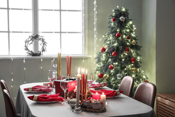 Burning candles and festive Christmas table setting in room interior