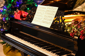 Fototapeta na wymiar Beautiful grand piano decorated for Christmas with notes in room, closeup