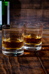 Glasses of strong scotch single malt whisky served on dark wooden table in old pub