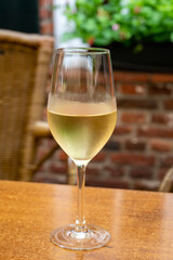 Glass of cold white wine served on outdoor terrace in old French cafe