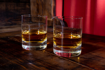 Glasses of strong scotch single malt whisky served on dark wooden table in old pub