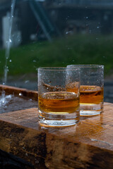 Glasses of strong scotch single malt whisky and rain water drops