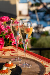 Russian style party with two glasses of white cold champagne, bliny with red caviar and view on Port Grimaud near Saint-Tropez in summer