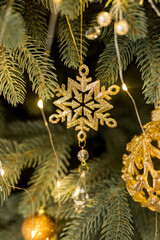 Close up of holidays location with gold snowflake toy and garlands on green Christmas tree