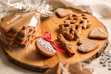 Wooden board with tasty Christmas gingerbread cookies on light background