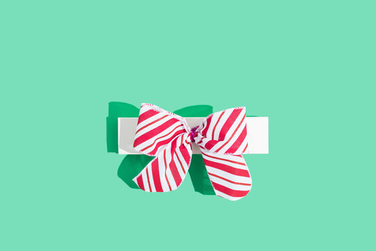 Jewelty box with large red and white bow on green teable background.  Flat lay, top view, minimal concept.