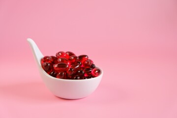 Krill oil capsules in a spoon on a light pink background. omega fatty acids.Natural supplements and...