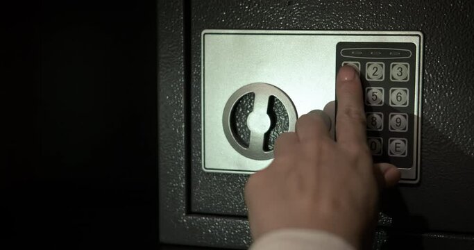 Use safe in the hotel. A travaler woman hand try to open a safe deposit in the room.