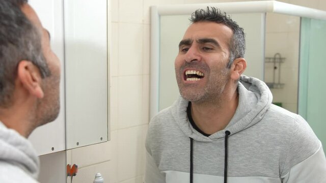 Dirty teeth and unhappy man. The unhappy state of the man looking at his teeth in the mirror. His yellowed teeth stand out.