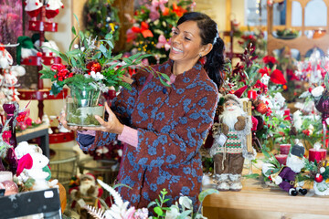 Hispanic woman selecting decorative new year goods in shop.