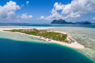 Aerial view of Maiga island panorama, beautiful blue lagoon and coral reef.