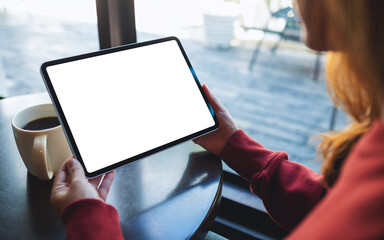 Mockup image of a woman holding digital tablet with blank white desktop screen in cafe