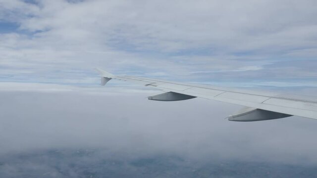 View of the plane wing through the airplane window. Air Transportation flying over the cloud