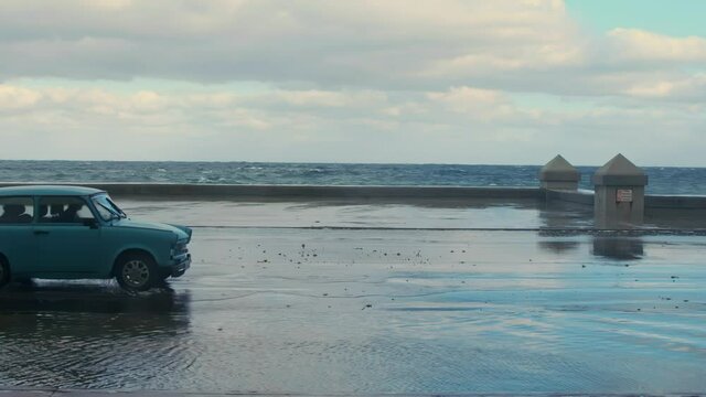 russian car driving on the malecon with ocean waves, Havana, Cuba