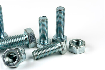 Large metal nuts with silver metal bolts. Close-up on a white background. A group of several nuts and bolts