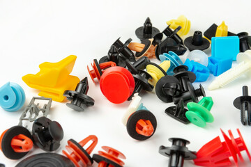 Close-up shot of plastic colored clips for the car.Abstract background. Panel plastic rivets isolated on white background. Auto plastic clasps. Insulated clip or automatic plastic clasp