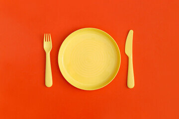 Plate with fork and spoon on a red background. Top view. Flat lay.
