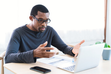 Confident African American bearded man wearing glasses work at home while talking video call...