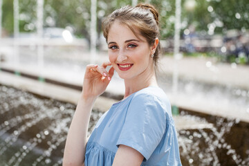 Fototapeta premium Young beautiful woman in a luxurious turquoise dress posing on the street