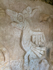 Mayan carving of a bird in a city of ruins.