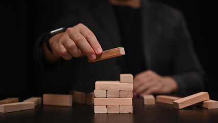 Businessman placing wooden block on a tower. Strategy and start up business concept.