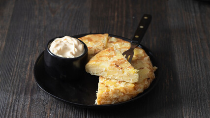 Traditional Spanish tapa,Tortilla  made with eggs and potatoes and served with mayonnaise on wooden table