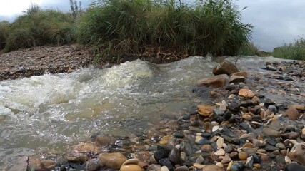 Fast flowing torrent of water over a pebble beach