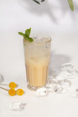 Glass of iced eggnog garnished with fresh mint on white background