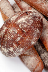 Freshly baked round wheat bread and whole grain baguettes isolated on white