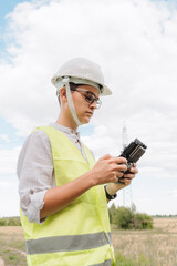 A young Engineer examines the high-voltage tower with a drone.