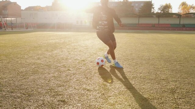 Energetic young black girl at football training in the stadium doing ball control exercises and deftly doing kick feints