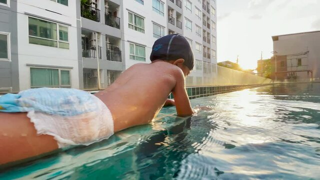Happy asian boy joyful swim in swimming pool sunset light little boy sport relax  