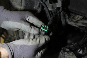 Close-up of the hands of an auto mechanic engaged in car maintenance. Car wiring with adapters and...