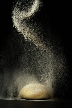 flour sprinkled on dough on a black background.