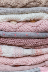 Fototapeta na wymiar A stack of knitted baby hats and snoods in beige and pink shades