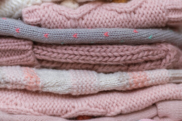 Fototapeta na wymiar A stack of knitted baby hats and snoods in beige and pink shades