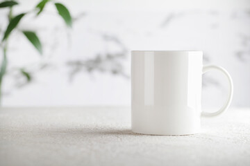 Obraz na płótnie Canvas Mug mockup with green plant on white background. Copy space selective focus. Blank cup for your design. space for your text, image and logo.
