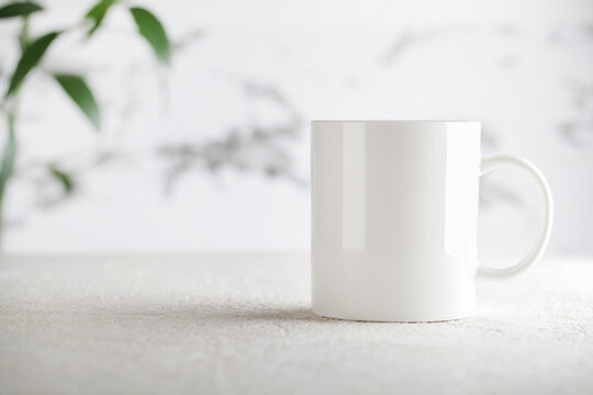 Mug mockup with green plant on white background. Copy space selective focus. Blank cup for your design. space for your text, image and logo.