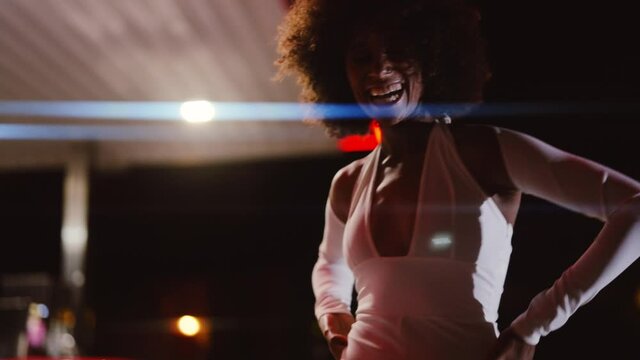 Woman With Afro In Jumpsuit Posing In Gas Station At Night