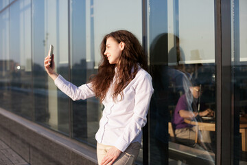 woman with mobile phone using technology for video chatting or social media or taking selfie in the city