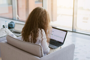 Young woman working on laptop in the public pplace. Caucasian woman with brown hair in the office and using laptop. Laptop screen