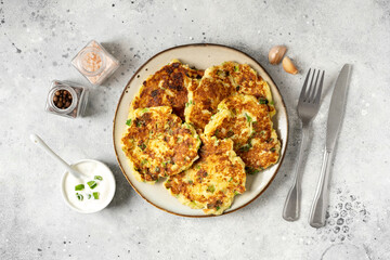 Homemade potato pancakes with cottage cheese and green onions in a ceramic plate on a bright kitchen table close-up. A traditional dish of European cuisine made of vegetables	