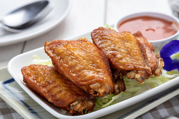 Deep fried fish sauce chicken wingettes (wing flats) served with chili sauce, a simple Thai food dish that can be found everywhere in Thailand from street food carts to restaurants.