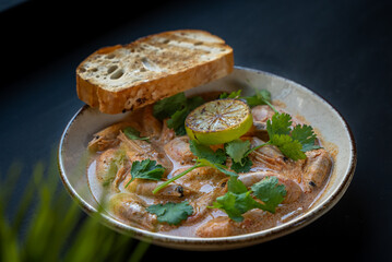 Appetizer with shrimps served with greens and toast on white plate on black background. Delicious, beautiful, healthy snack. Modern cuisine