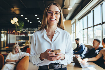 Jeune femme d& 39 affaires tenant un smartphone dans un espace de coworking