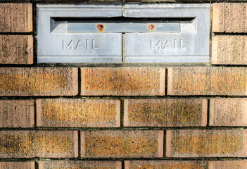 Metal old style mailbox on red brick walls.