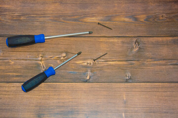 On the brown floor there are two screwdrivers with blue handles and two black screws. Locksmith...