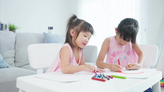 Asian young girl children drawing and coloring paper in living room.