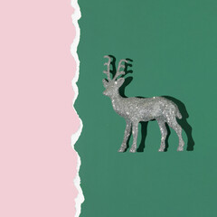 Christmas creative layout with silver reindeer decoration on dark green and pastel pink background....