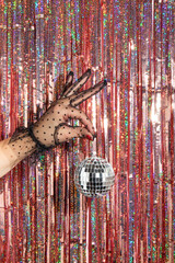 Christmas creative layout with woman hand in lace glove holding disco ball decoration infont of...